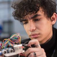 A student inspects a robot